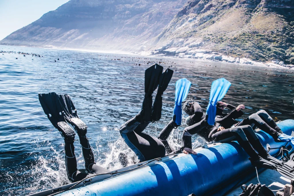 five snorkelers back roll into the ocean