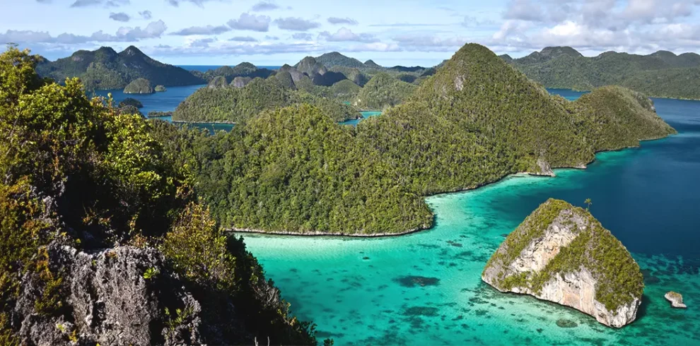 A scenic view of Piaynemo in Raja Ampat with turquoise waters, green islands, and limestone formations.